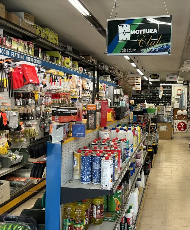 Corsia del negozio con scaffali di vernici, utensili e l'insegna per la duplicazione delle chiavi protette